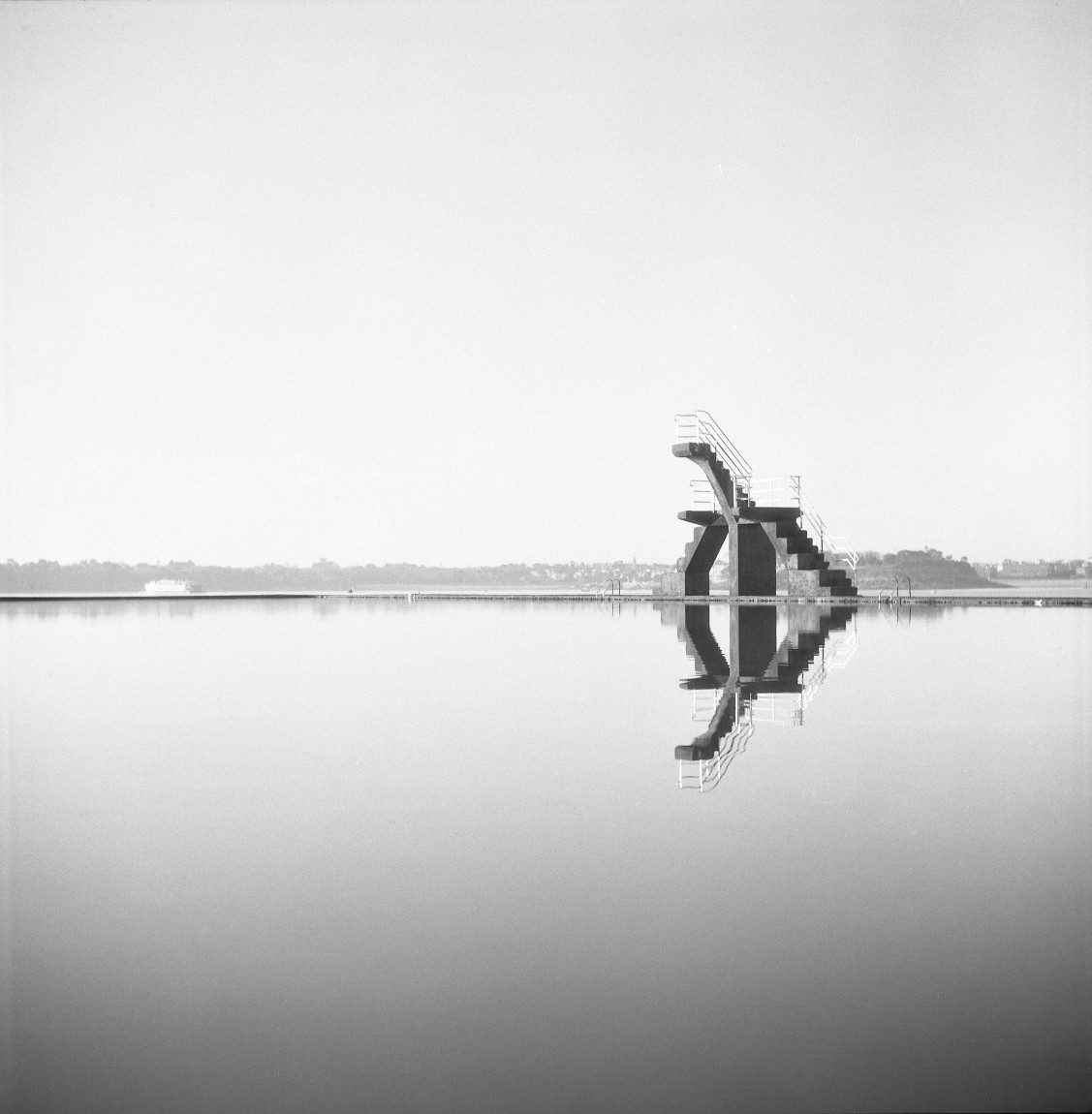 Impareils, photographie argentique noir et blanc d’un plongeoir sur une eau calme